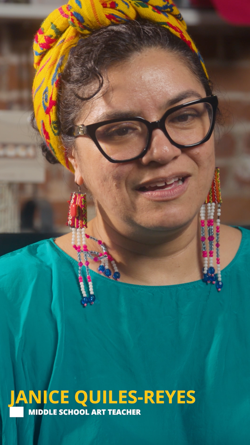 woman wearing head wrap and glasses seated in front of blurred background